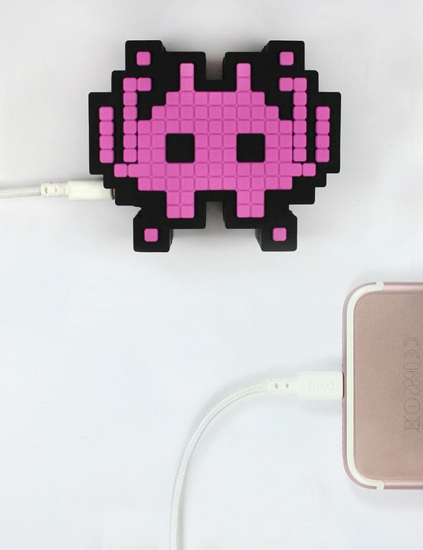 Moji Power Bank Invaders with the pink side facing top is used to charging a phone